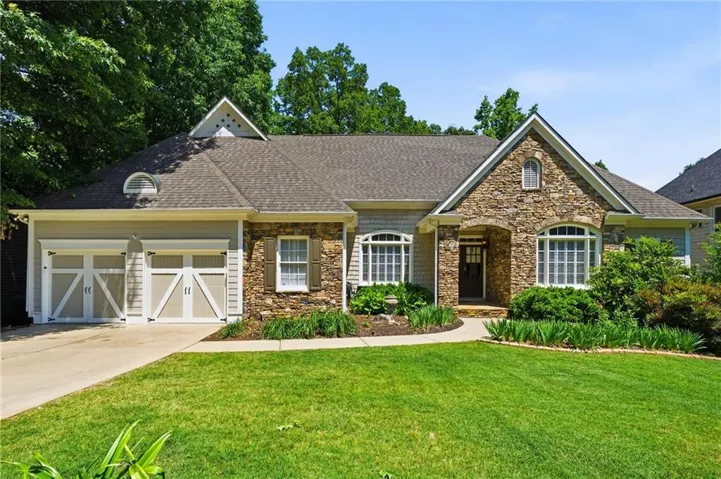 Stone and siding exterior featuring a covered entry, arched windows, and decorative garage doors