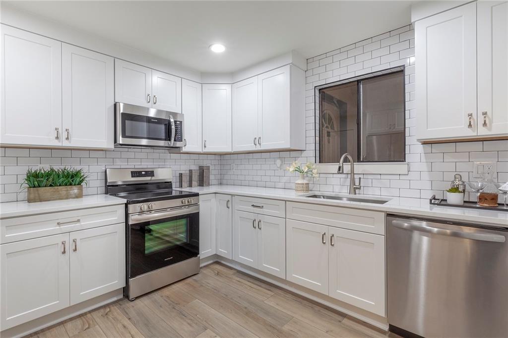 Kitchen featuring tasteful backsplash, white cabinetry, and stainless steel appliances