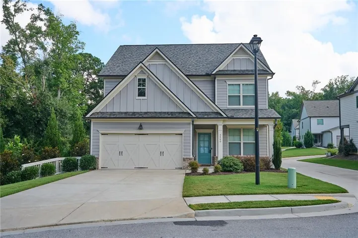 Two-story home with a light gray siding exterior, an attached two-car garage, and a peaked roofline