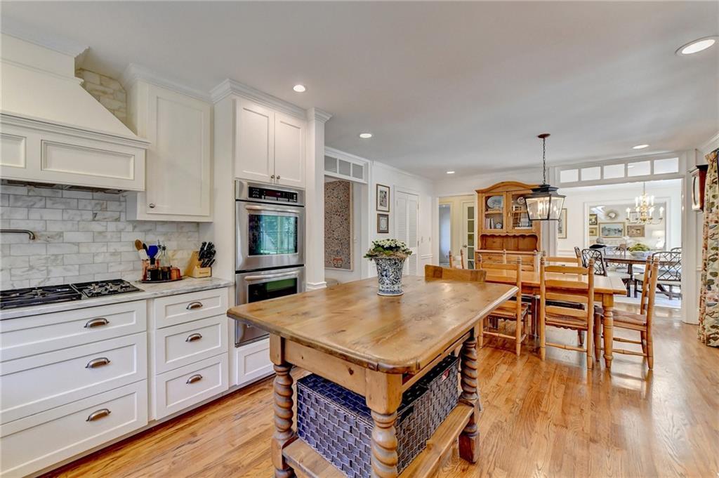 Kitchen with light hardwood / wood-style floors, white cabinets, a notable chandelier, stainless steel appliances, and pendant lighting
