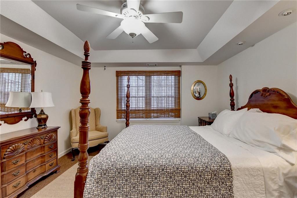 Bedroom with multiple windows, carpet floors, ceiling fan, and a raised ceiling