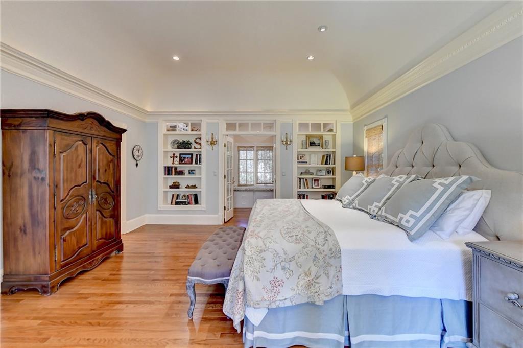 Bedroom with light hardwood / wood-style floors, vaulted ceiling, and crown molding