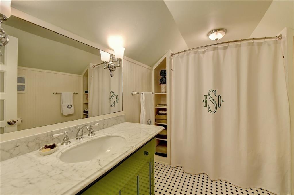Bathroom featuring vaulted ceiling, oversized vanity, and tile flooring