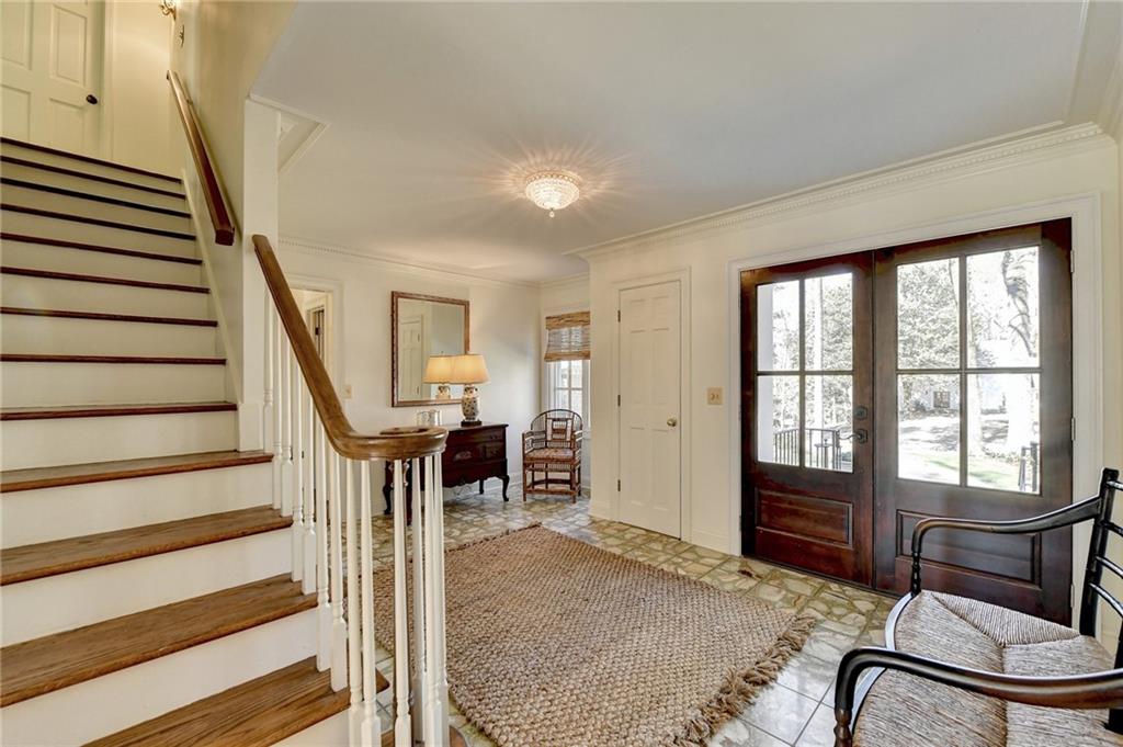 Tiled foyer with ornamental molding and french doors