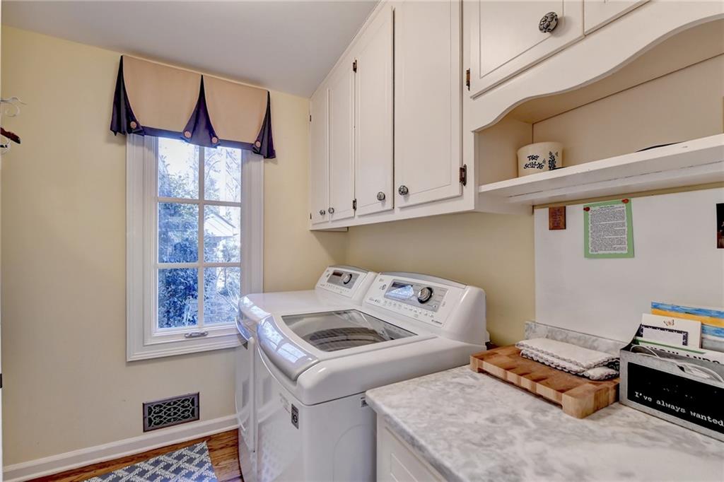 Laundry room with a wealth of natural light, wood-type flooring, washing machine and clothes dryer, and cabinets
