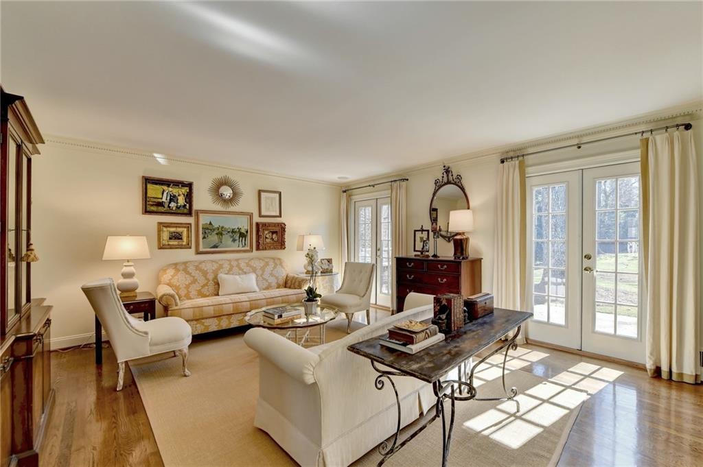 Living room with a wealth of natural light, light hardwood / wood-style floors, crown molding, and french doors
