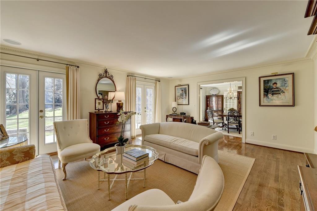 Living room featuring light wood-type flooring, a wealth of natural light, crown molding, and french doors