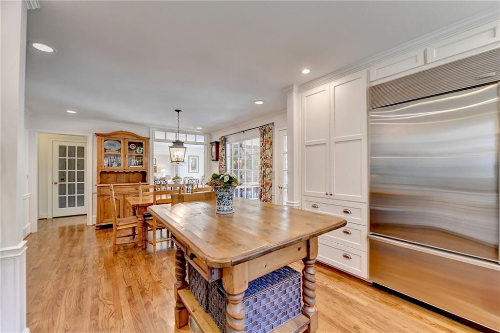 Kitchen featuring white cabinets, stainless steel built in fridge, pendant lighting, and light hardwood / wood-style flooring