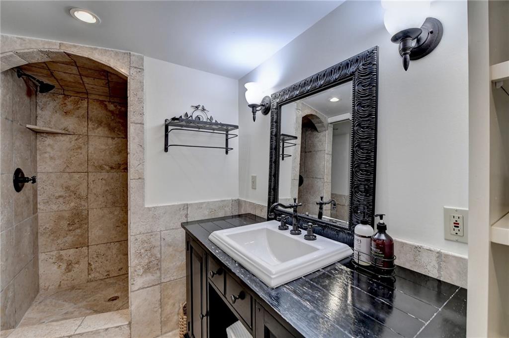 Bathroom featuring vanity with extensive cabinet space and tiled shower