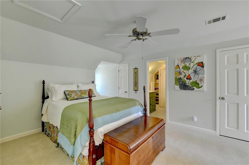 Bedroom featuring connected bathroom, lofted ceiling, ceiling fan, and light carpet