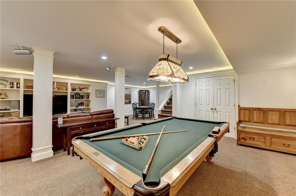 Recreation room with crown molding, built in shelves, billiards, light carpet, and decorative columns