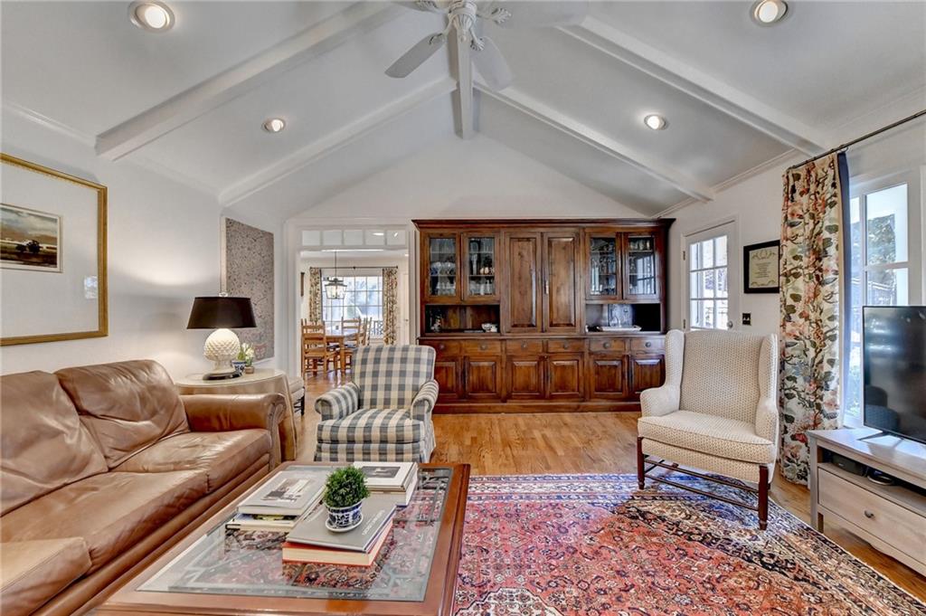 Living room featuring light hardwood / wood-style flooring, vaulted ceiling with beams, and ceiling fan