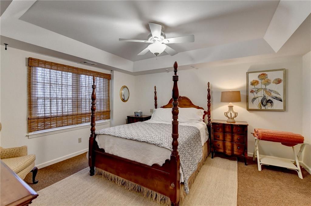 Carpeted bedroom featuring ceiling fan and a raised ceiling