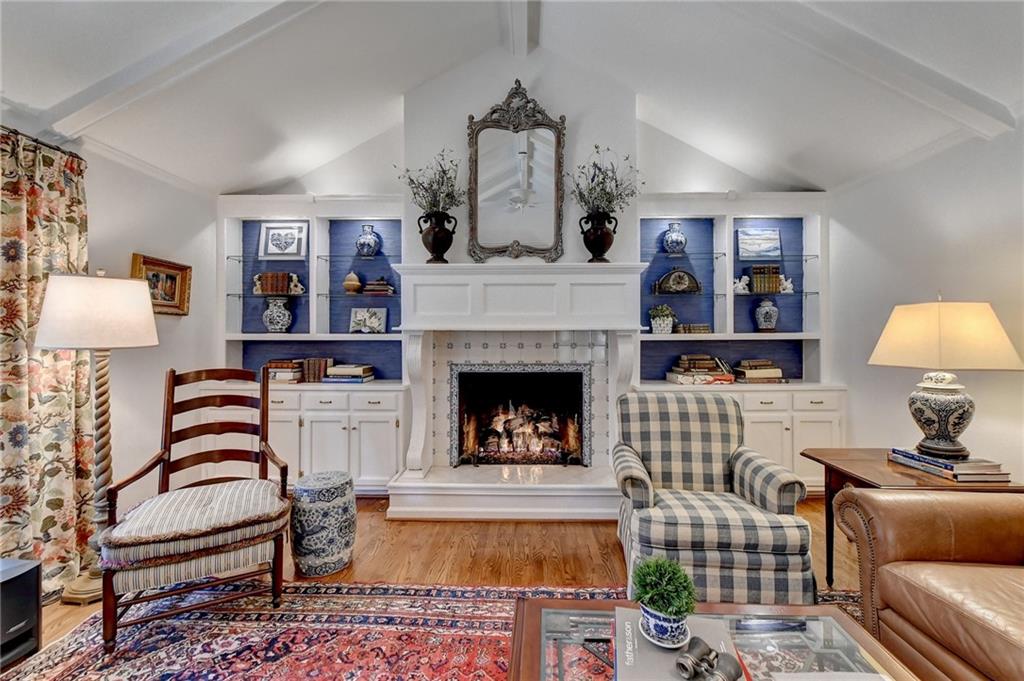 Living room featuring lofted ceiling with beams, a fireplace, and light wood-type flooring