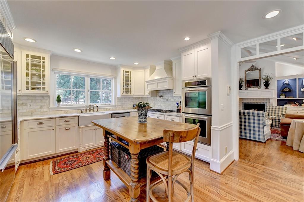 Kitchen featuring premium range hood, light wood-type flooring, white cabinetry, appliances with stainless steel finishes, and sink