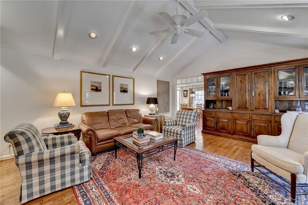 Living room featuring lofted ceiling with beams, light hardwood / wood-style floors, and ceiling fan