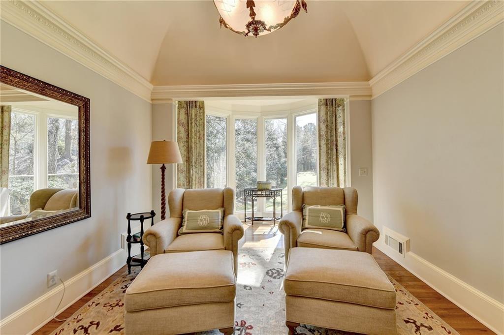 Living area featuring vaulted ceiling, dark hardwood / wood-style flooring, plenty of natural light, and crown molding