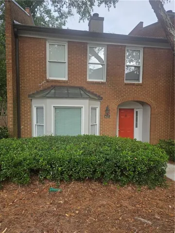 Brick facade townhome featuring a prominent red entry door