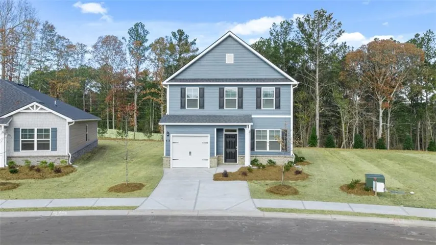 Two-story Colonial-style home featuring a light blue exterior with white trim, paired windows, and a peaked roofline