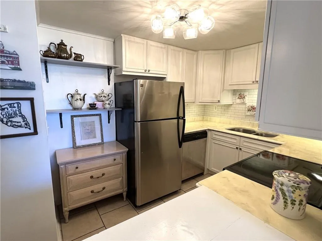 Charming kitchen with beautiful counter tops, stainless appliances, tile backsplash, & new light fixture