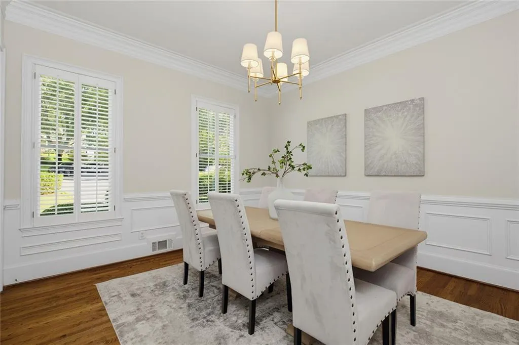 Hardwood flooring, decorative wainscoting, crown molding, plantation shutters, and a brass chandelier