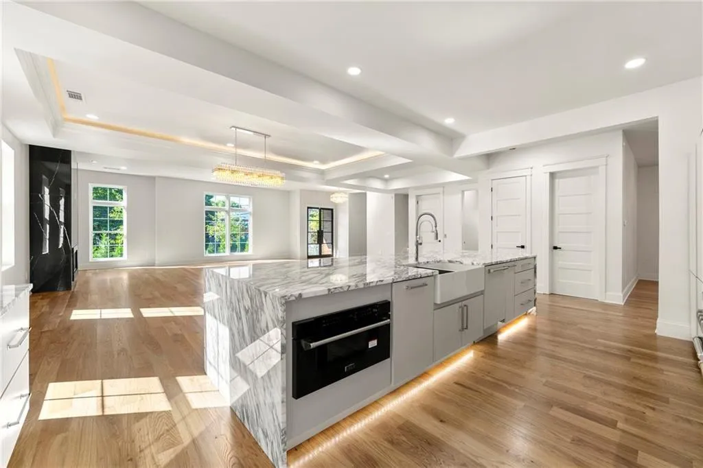 Kitchen with a spacious island, light wood-flooring, marble countertops, and recessed lighting Kitchen with a spacious island, light wood-flooring, marble countertops, and recessed lighting