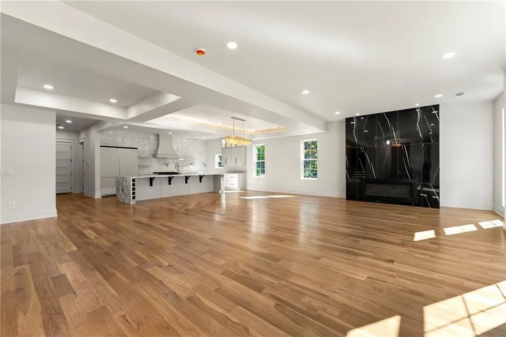 Living room with a raised ceiling, light wood-flooring, recessed lighting, and a premium fireplace Living room with a raised ceiling, light wood-flooring, recessed lighting, and a premium fireplace