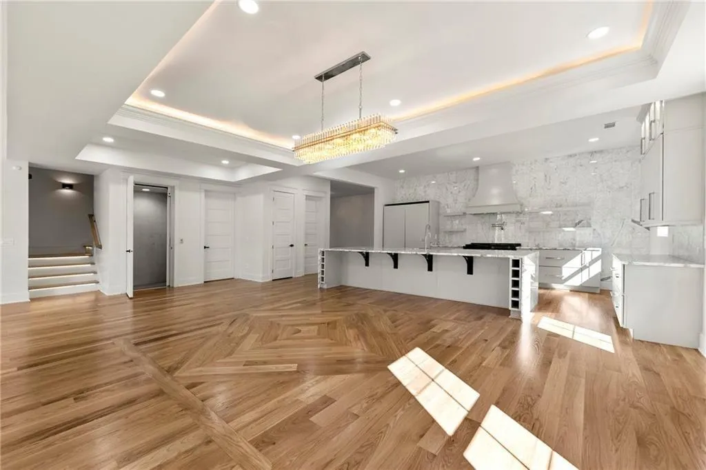 Living room featuring a tray ceiling, stairs, recessed lighting, crown molding, and wood floors