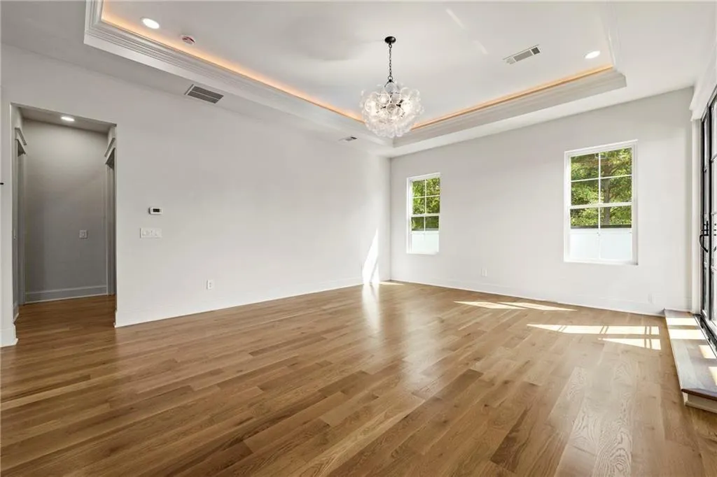 Primary suite featuring a raised ceiling, light wood-floors, a chandelier, recessed lighting, and ornamental molding Primary suite featuring a raised ceiling, light wood-floors, a chandelier, recessed lighting, and ornamental molding