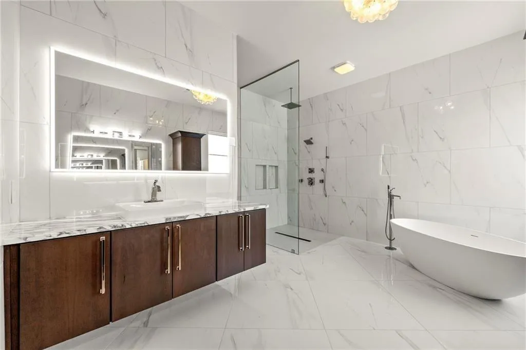 Primary bathroom featuring tile walls, vanity, a marble finish shower, a freestanding bath, and light marble finish flooring, and walk in shower. Primary bathroom featuring tile walls, vanity, a marble finish shower, a freestanding bath, and light marble finish flooring, and walk in shower.