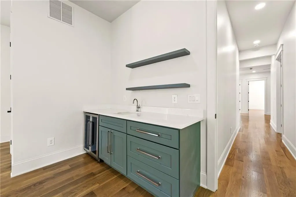 Flex room Bar on second level with open shelves, green cabinets, dark wood finished floors, light stone countertops, and wine cooler