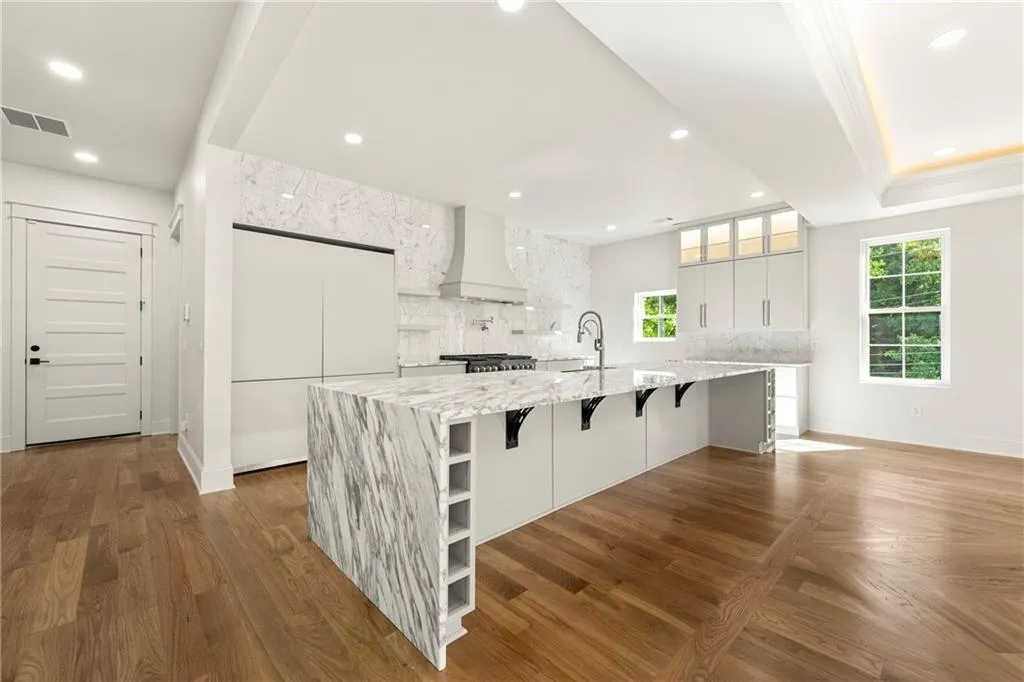 Kitchen featuring a breakfast bar area, white cabinets, recessed lighting, marble countertops, and glass insert cabinets Kitchen featuring a breakfast bar area, white cabinets, recessed lighting, marble countertops, and glass insert cabinets