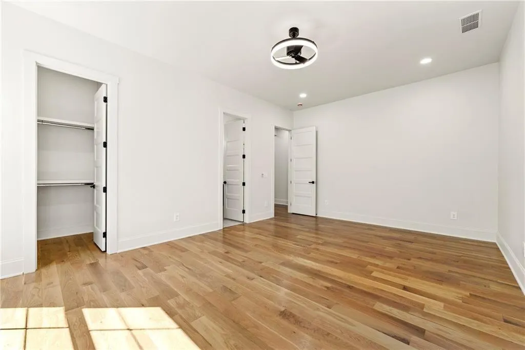 Bedroom #3 view with light wood flooring, a spacious closet, and recessed lighting, custom closet and ensuite bath.