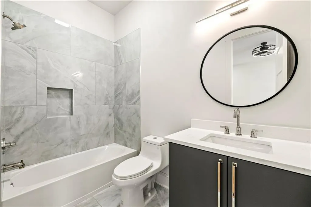 Full bathroom featuring bathtub / shower combination, vanity, and light marble finish flooring Full bathroom featuring bathtub / shower combination, vanity, and light marble finish flooring