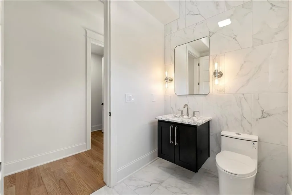 Half Bathroom with vanity, tile walls, and light marble finish flooring Half Bathroom with vanity, tile walls, and light marble finish flooring