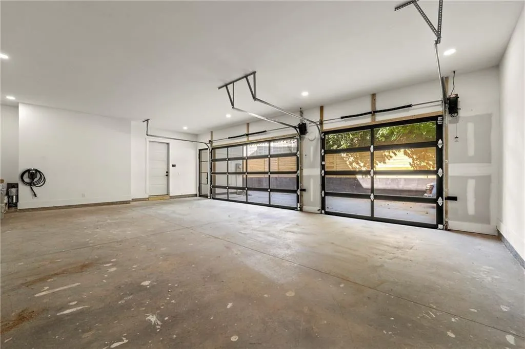 Garage featuring baseboards and recessed lighting, EV charger and state-of-the-art doors and equipment. Garage featuring baseboards and recessed lighting, EV charger and state-of-the-art doors and equipment.