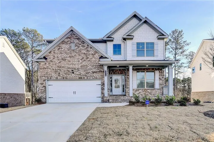 Two-story residence featuring a brick and shake siding facade, a two-car garage, and a covered front porch with columns