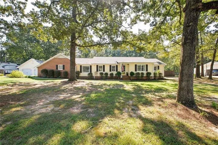 Ranch-style residence featuring a pale yellow facade, dark shutters, and a covered porch