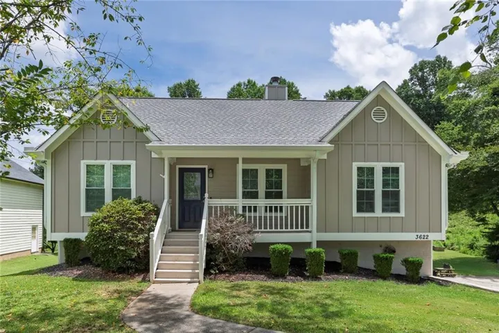 Board and batten siding, covered front porch, gabled rooflines, concrete walkway, and landscaped shrubbery
