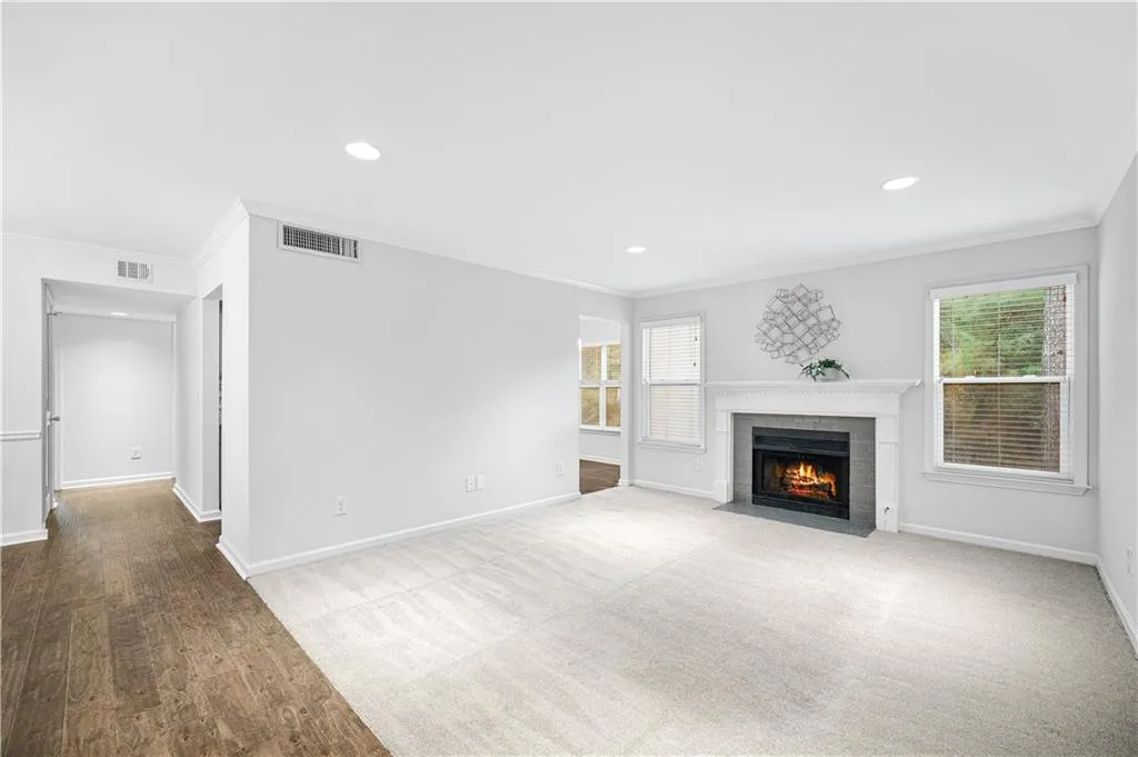 Unfurnished living room featuring ornamental molding, a fireplace, recessed lighting, carpet flooring, and wood finished floors