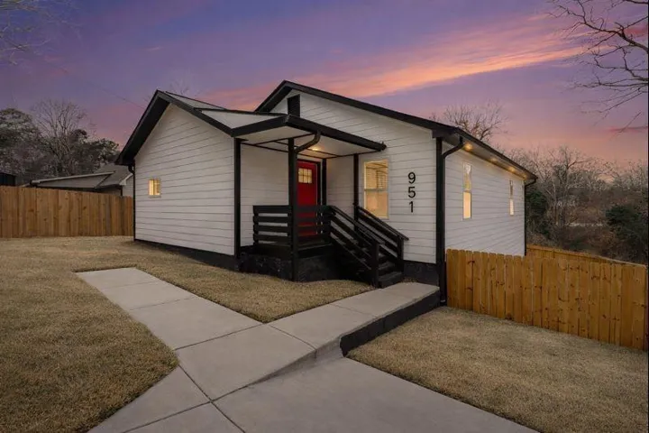 Modern farmhouse-style exterior with white siding, black trim, and a vibrant red front door