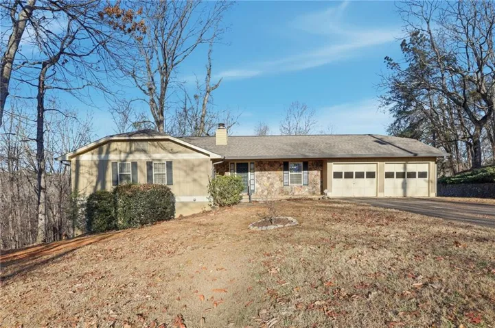 Single story home featuring a chimney, asphalt driveway, an attached garage, a shingled roof, and stone siding