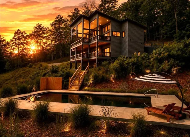 Modern architecture with expansive window walls, multi-level balconies, a built-in swimming pool, and concrete hardscaping