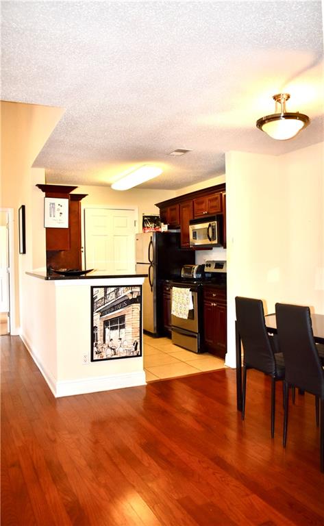 Kitchen with light tile flooring, a textured ceiling, and stainless steel appliances