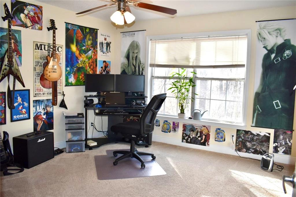 Carpeted home office with plenty of natural light and ceiling fan