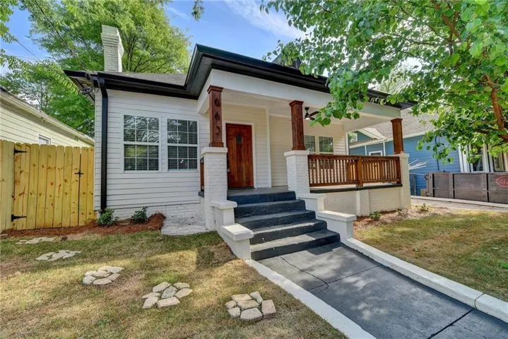 Charming cottage-style home featuring a freshly updated exterior with crisp white siding, black architectural accents, and burgundy entry doors