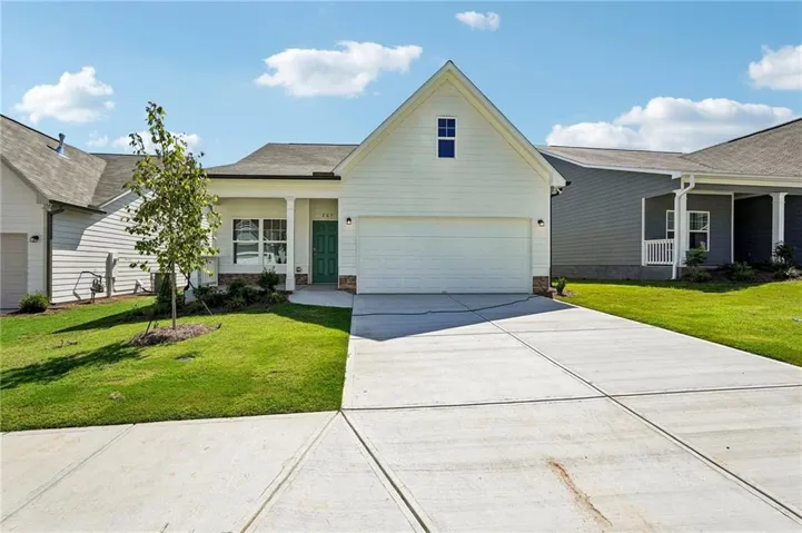 White siding exterior with a prominent gable, attached two-car garage, and a concrete driveway