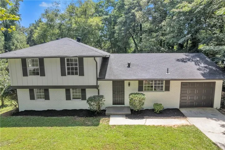 Split level home with a garage, a front lawn, concrete driveway, and board and batten siding
