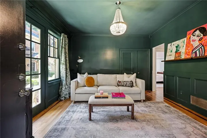 Hardwood flooring, paneled walls, a crystal chandelier, and a built-in wall shelf