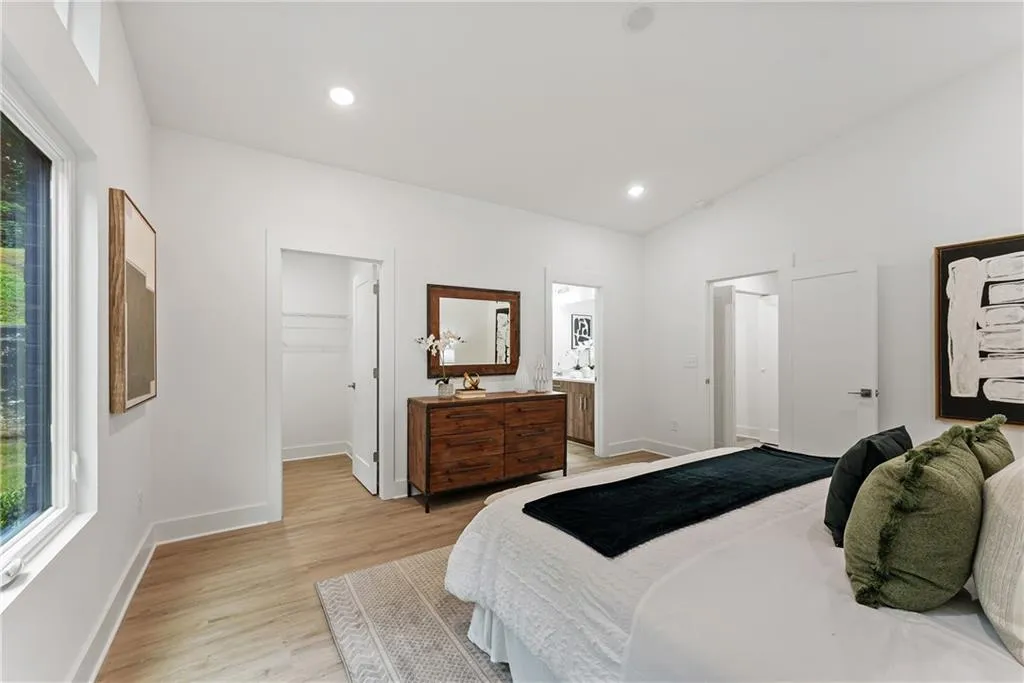 Bedroom with a spacious closet, light wood-style floors, recessed lighting, and connected bathroom